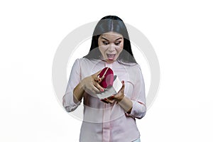 Extremely surprised asian woman is opening a heart-shaped gift box.