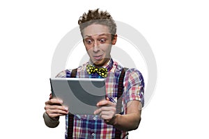 Extremely surprised teenage boy`s looking at tablet pc screen.