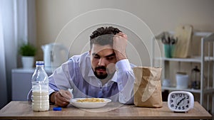 Extremely tired young bachelor sleeping over plate with corn flakes avitaminosis