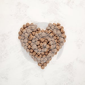 Extruded Rye Bran in heart shape on grey textured background. Crunchy snack for breakfast. Rye bran is Trendy Healthy food