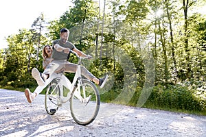 Exuberant couple sharing a bicycle in nature photo