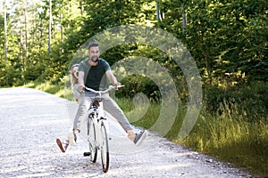 Exuberant couple sharing a bicycle in rural landscape photo