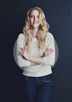 She exudes a sense of confidence. Studio portrait of a smiling young woman isolated on black.