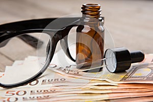 eye care concept - reading glasses, eye drops and money