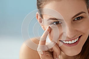 Eye care. Smiling woman with contact eye lens on finger closeup