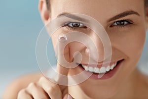 Eye care. Smiling woman with contact eye lens on finger closeup