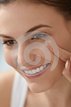 Eye care. Smiling woman with contact eye lens on finger closeup