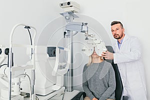 Eye doctor checking patient`s eyes on a machine.