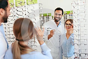 Eye Doctor With Woman Choosing Eyeglasses At Glasses Store