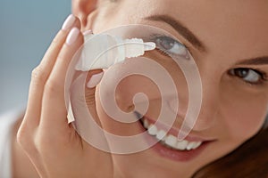 Eye drop. Woman applying lubricant eye drops in her eyes closeup photo