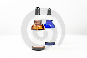 Eye dropper bottles with blank white label, in brown and blue, depicting medicine, formula or administration of a liquid drug or