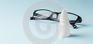 Eye drops bottle with eyeglasses on blue background