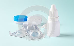 Eye drops with contact lenses and accessories on blue background