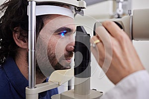 Eye exam, care or laser test for patient with machine at optometry consultation for lens or vision. Face of man and