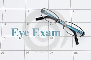 Eye exam doctor appointment with glasses and sticky note on a calendar