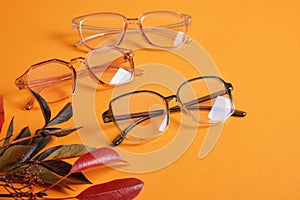 eye glasses nad red autumn leaves on orange background copy space