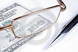 Eye-glasses, pen and banknote