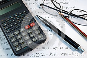 Eye Glasses, pen and pencil over the Formula with calculator