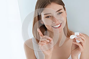 Eye lens. Smiling woman with contact eye lenses and container