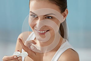 Eye lens. Smiling woman with contact eye lenses and container