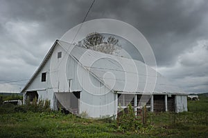 Eye-level gloomy shot of an old white barn on a cloudy day