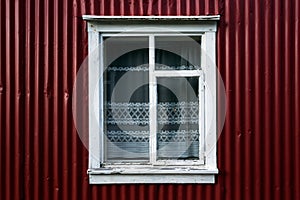 Eye-level shot of the facade of a red building with a white framed window