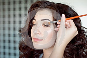 Eye makeup woman applying eyeshadow powder. Make up artist doing professional make up of young woman