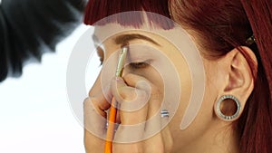 Eye makeup woman applying eyeshadow powder. Stylist is doing make up for female by eyeliner