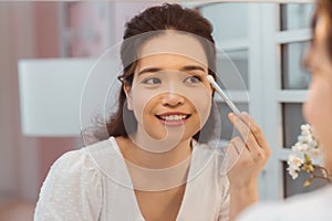 Eye makeup woman applying eyeshadow powder. Young beautiful woman making make-up near mirror, sitting at the desk