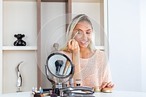 Eye makeup woman applying eyeshadow powder. Young beautiful woman making make-up near mirror,sitting at the desk