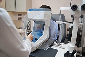 Eye physician checking man sight with autorefractor photo
