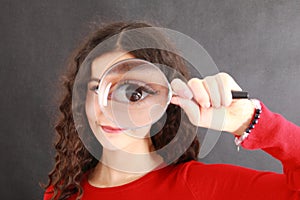 Eye of pretty young teen girl in magnifying glass