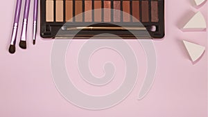 Eye shadow palette and set of makeup brushes, makeup accessories on pastel pink background. Classic shades. minimal