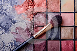 Eye shadow palettes with a variety of shades, accompanied by a professional make-up brush, set against a clean, minimalist