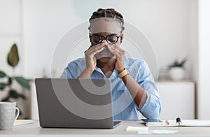 Eye Strain. Tired African Female Office Worker Sitting At Workplace Massaging Nosebridge