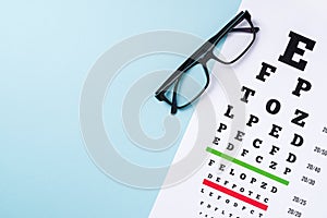 Eye test chart and glasses on blue background