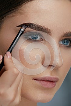Eyebrow coloring. Woman applying brow tint with makeup brush