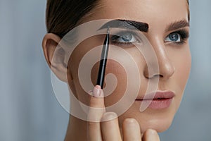 Eyebrow coloring. Woman applying brow tint with makeup brush