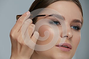 Eyebrow coloring. Woman applying brow tint with makeup brush