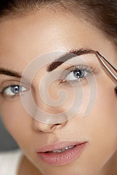 Eyebrow Correction. Closeup Of Beautiful Young Woman With Perfect Makeup And Long Lashes Plucking Eyebrows.