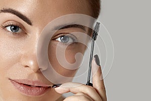 Eyebrow makeup. Beautiful woman shaping brows with brush   closeup.