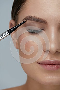 Eyebrow makeup. Beauty model shaping brows with brow pencil