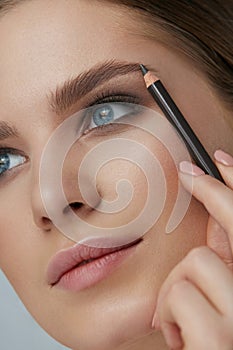 Eyebrow makeup. Beauty model shaping brows with brow pencil