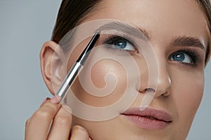 Eyebrow makeup. Beauty model shaping brows with brow pencil