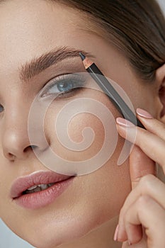 Eyebrow makeup. Beauty model shaping brows with brow pencil