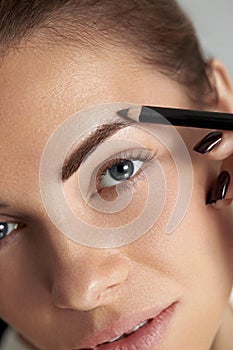 Eyebrow makeup. Beauty model shaping brows with brow pencil closeup.