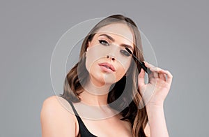 Eyebrow makeup. Woman brushing brows with brows brush closeup. Woman portrait isolated on gray studio background.