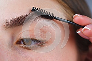 Eyebrow shaping. Close up of woman getting eyebrow make-up. Macro of combing eyebrows. Perfect shape of eyebrow, brown