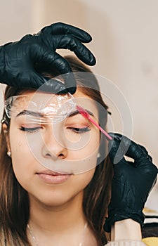 Eyebrow shaping procedure, make-up master uses brush to shape the eyebrows