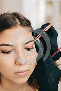 Eyebrow shaping procedure, make-up master uses tweezers and brush to shape the eyebrows